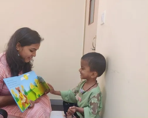 A therapist reading a picture book with a young boy